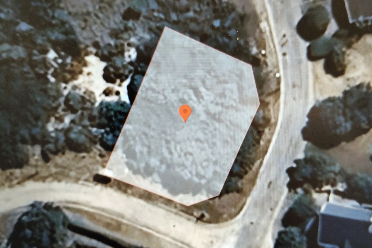 An aerial view of a vacant residential plot, highlighting the property boundaries and its location within the surrounding neighborhood.