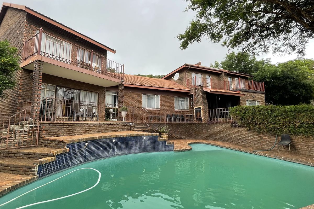 Rear view of a multi-story brick house featuring a swimming pool, upper-level balconies, and an outdoor fireplace area.