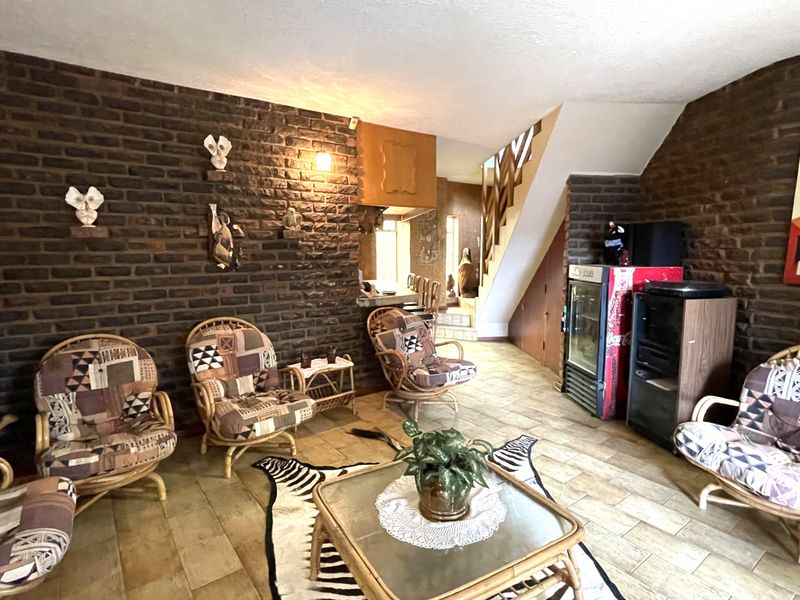 A living area featuring exposed brick walls, ceramic tile flooring, and an integrated staircase leading to the upper level.