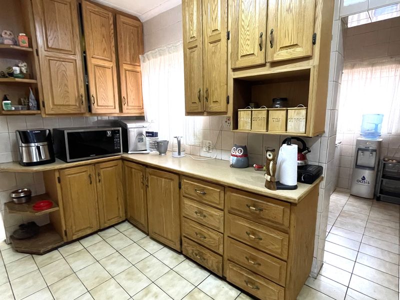 A functional kitchen featuring traditional oak cabinetry, laminate countertops, and ceramic tiled flooring and walls, offering a classic layout with ample storage space.