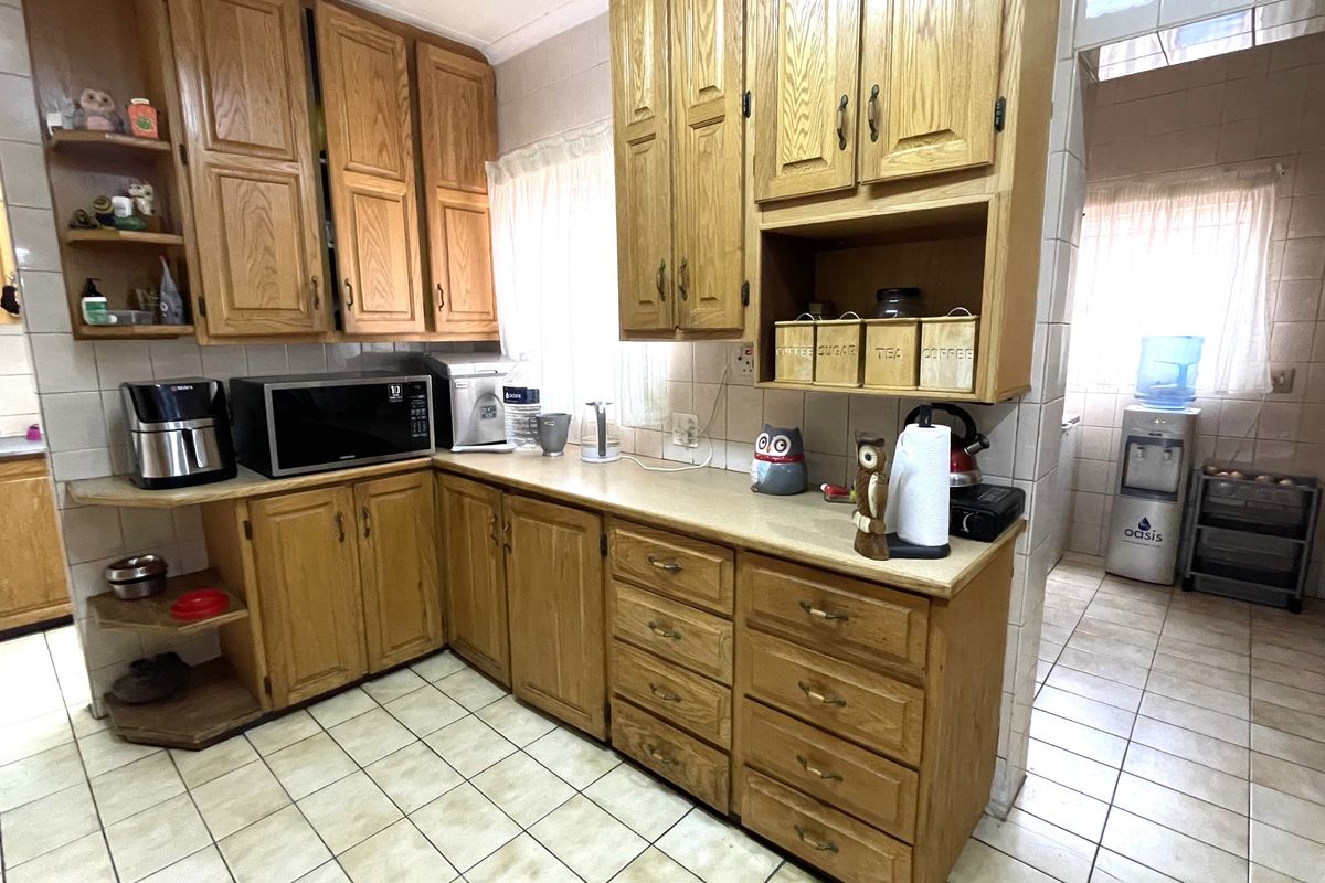 A functional kitchen featuring traditional oak cabinetry, laminate countertops, and ceramic tiled flooring and walls, offering a classic layout with ample storage space.