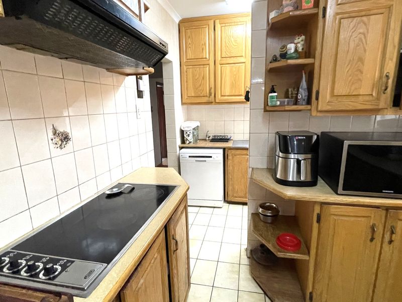 A functional kitchen featuring traditional wooden cabinetry, tiled backsplash, and integrated cooking appliances, offering a classic layout with potential for modern updates.