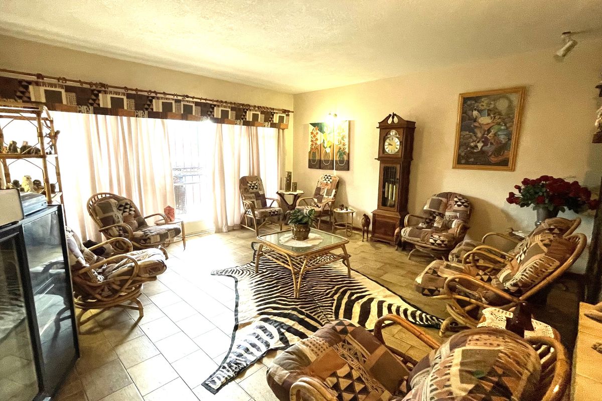 A spacious living room featuring tiled flooring, a stone fireplace, and large sliding glass doors that provide ample natural light.