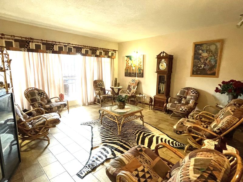A spacious living room featuring tiled flooring, a stone fireplace, and large sliding glass doors that provide ample natural light.