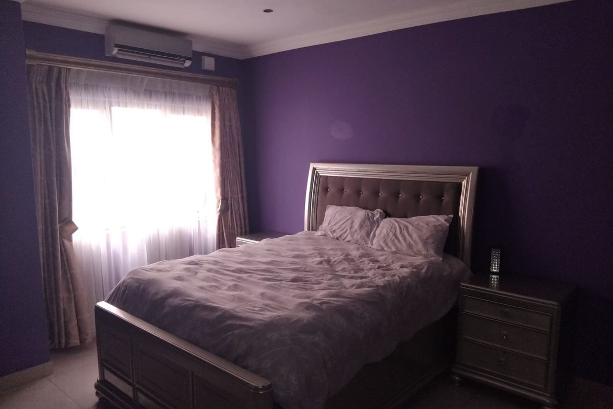 A bedroom featuring purple walls, tiled flooring, and a wall-mounted air conditioning unit.