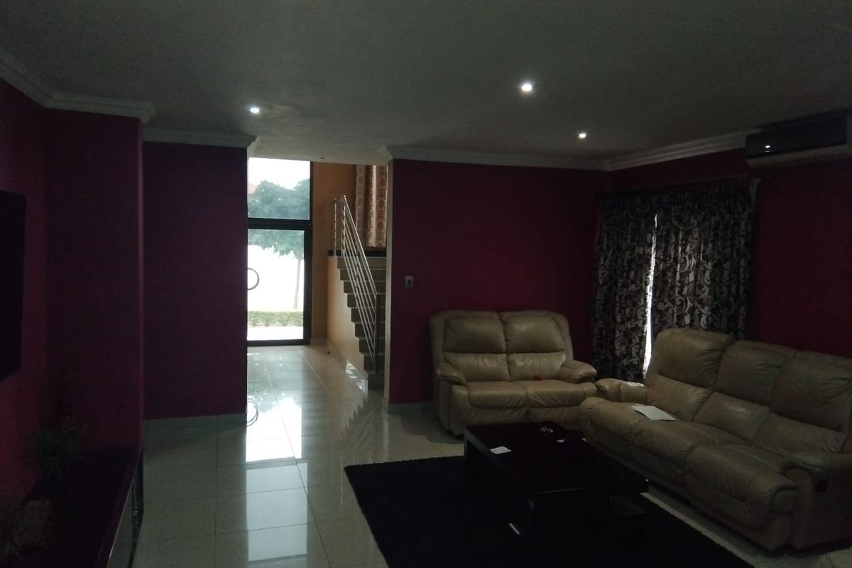 A spacious living room featuring tiled flooring, recessed ceiling lighting, and an integrated staircase leading to the upper level.