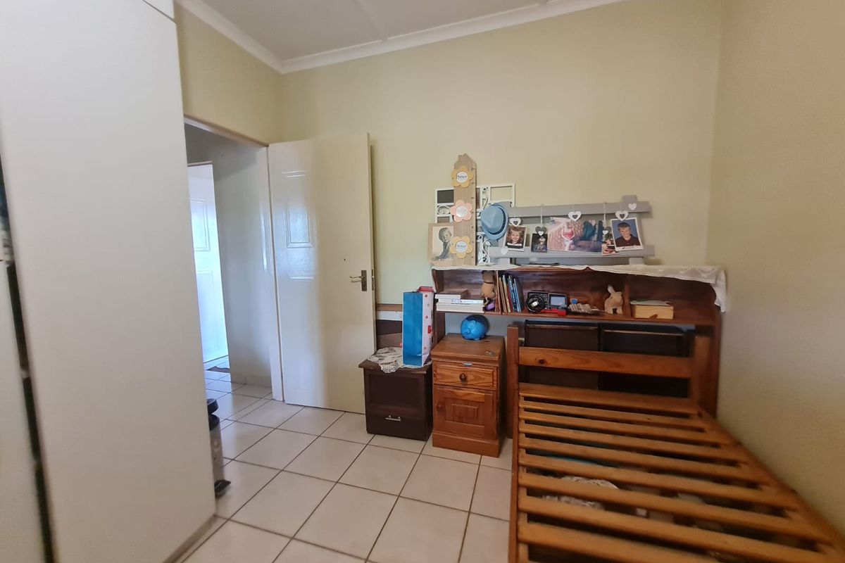 A bedroom featuring tiled flooring, built-in wardrobe storage, and access to an adjoining hallway.