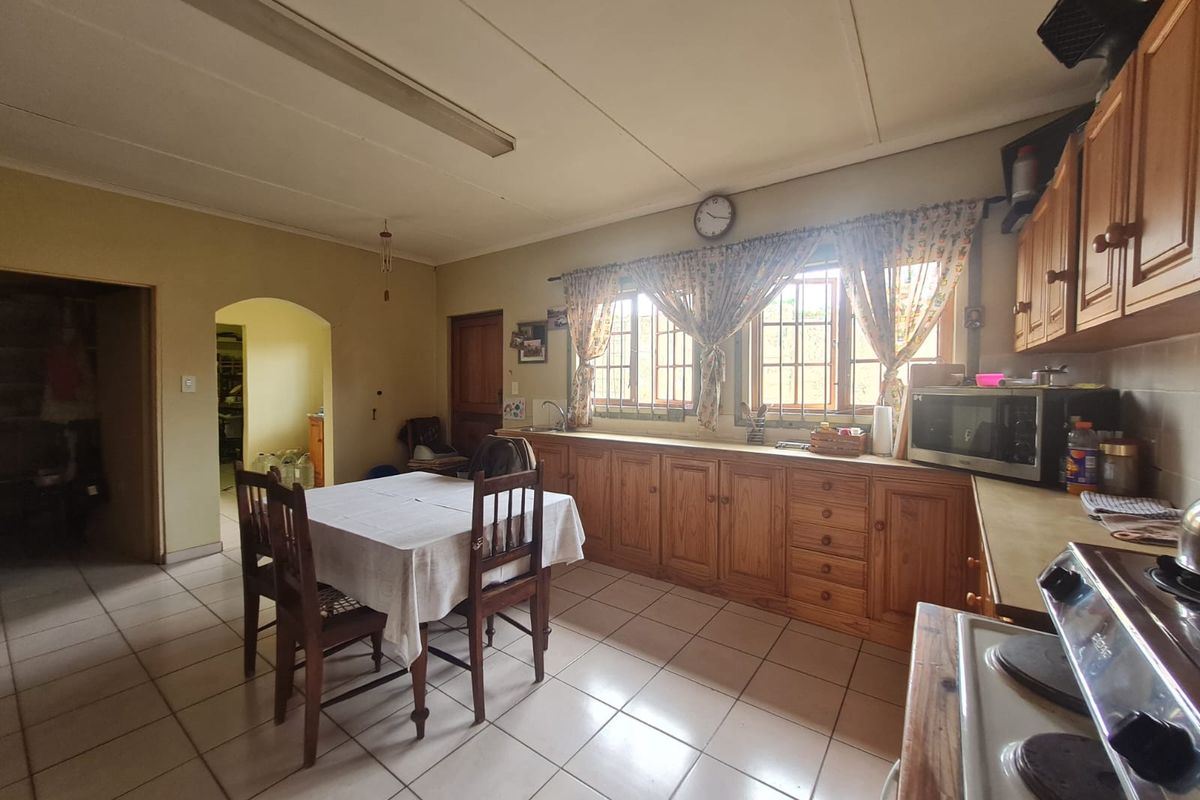 A functional kitchen featuring wooden cabinetry, tiled flooring, and a built-in stove, offering a practical layout with an adjacent dining area.