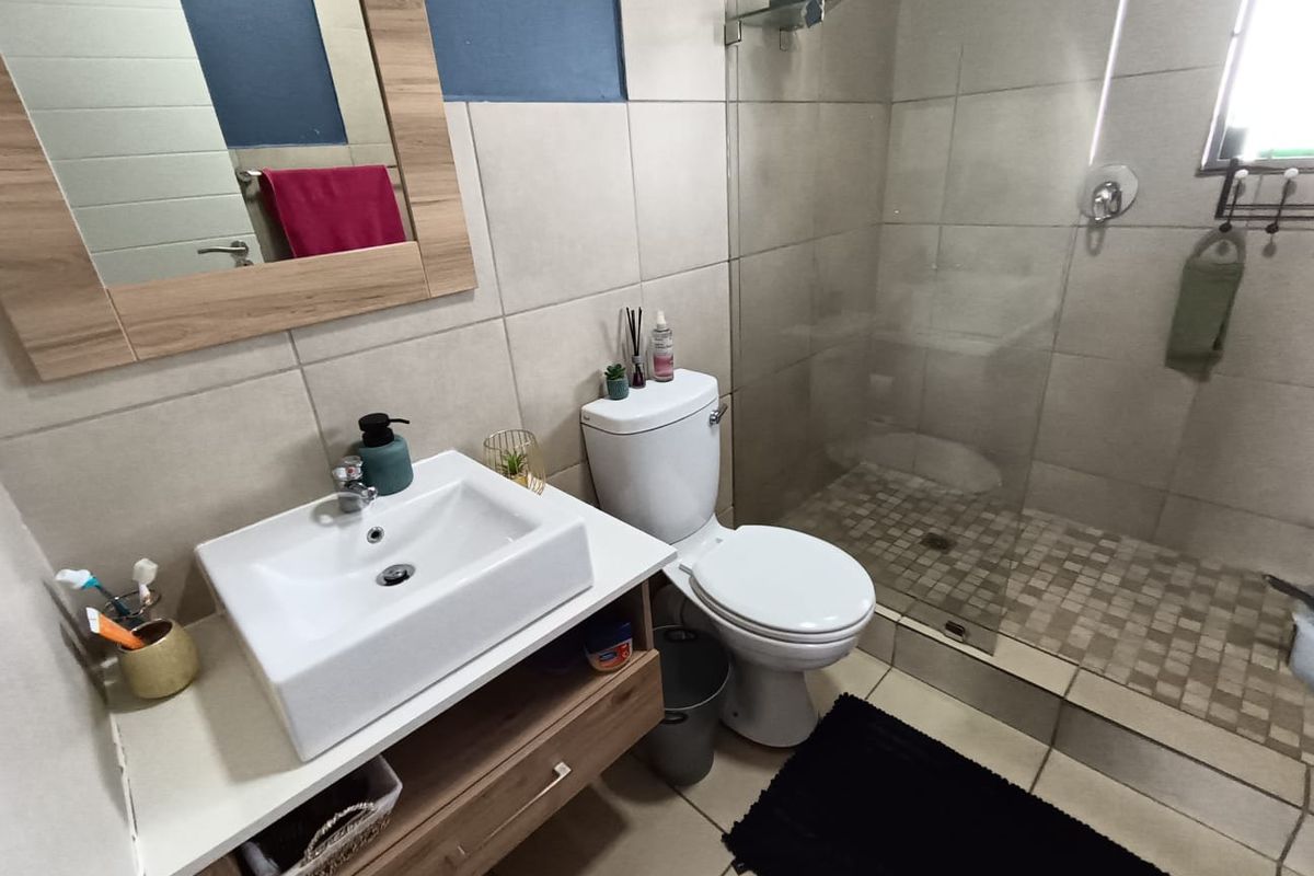 A modern bathroom featuring a vessel sink vanity, a toilet, and a walk-in shower with a glass screen and tiled finishes.