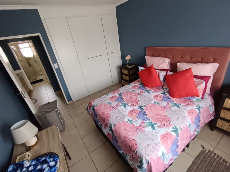 A well-maintained bedroom featuring built-in cupboards, tiled flooring, and direct access to an adjoining bathroom.