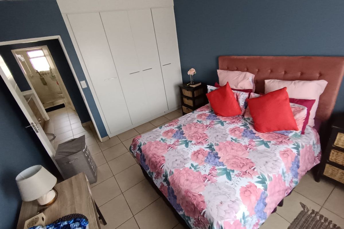 A well-maintained bedroom featuring built-in cupboards, tiled flooring, and direct access to an adjoining bathroom.