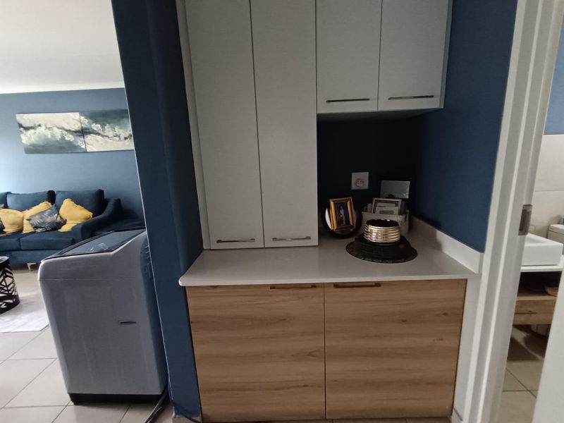 A functional laundry area featuring modern built-in cabinetry with a clean countertop, providing convenient storage and workspace within the apartment.