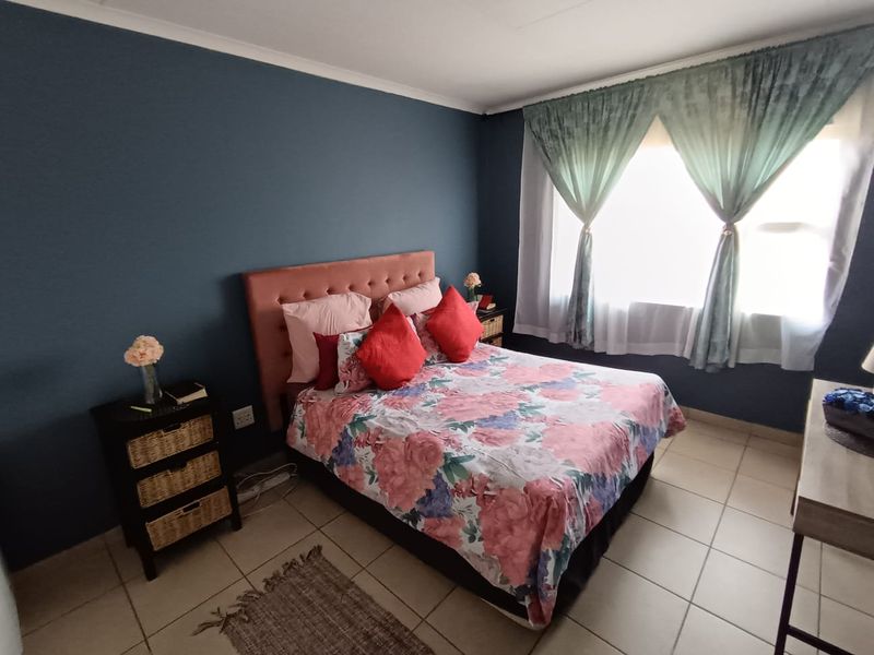 A bedroom featuring tiled flooring and a dark blue accent wall, providing a functional space with natural light.