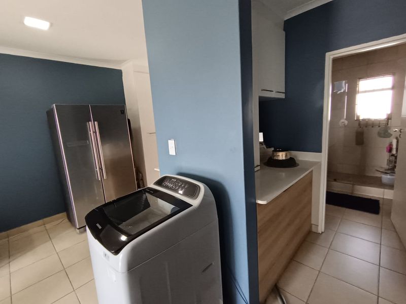 A functional laundry area featuring tiled flooring, built-in cabinetry with countertop space, and recessed lighting, providing a practical utility space within the apartment.
