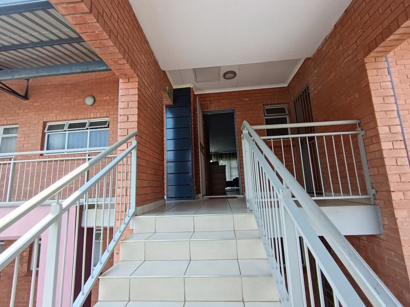 Exterior entrance area featuring a tiled staircase with metal balustrades leading to the main doorway of the apartment.