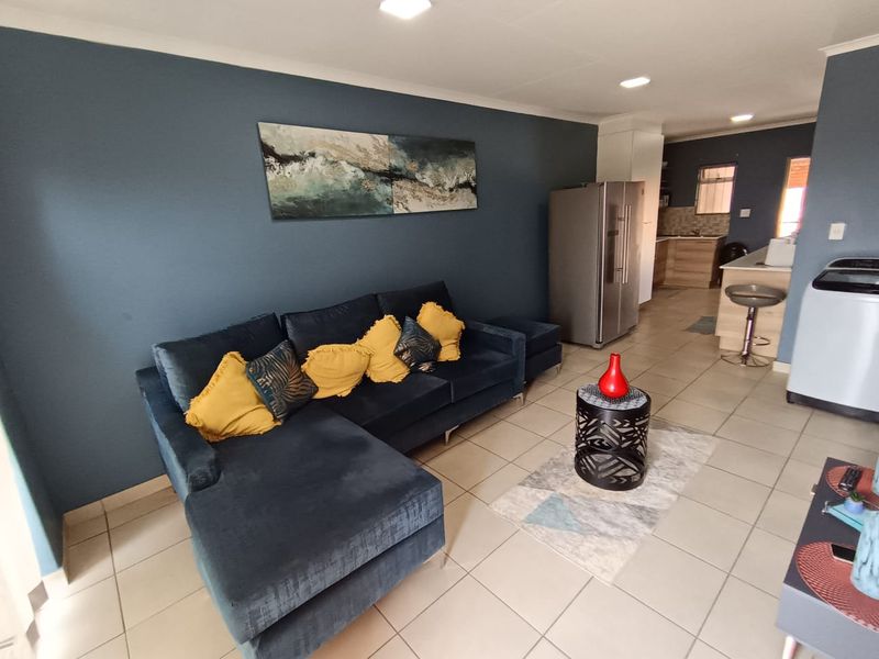 An open-plan living area featuring tiled flooring, recessed lighting, and a functional kitchen with a breakfast counter.