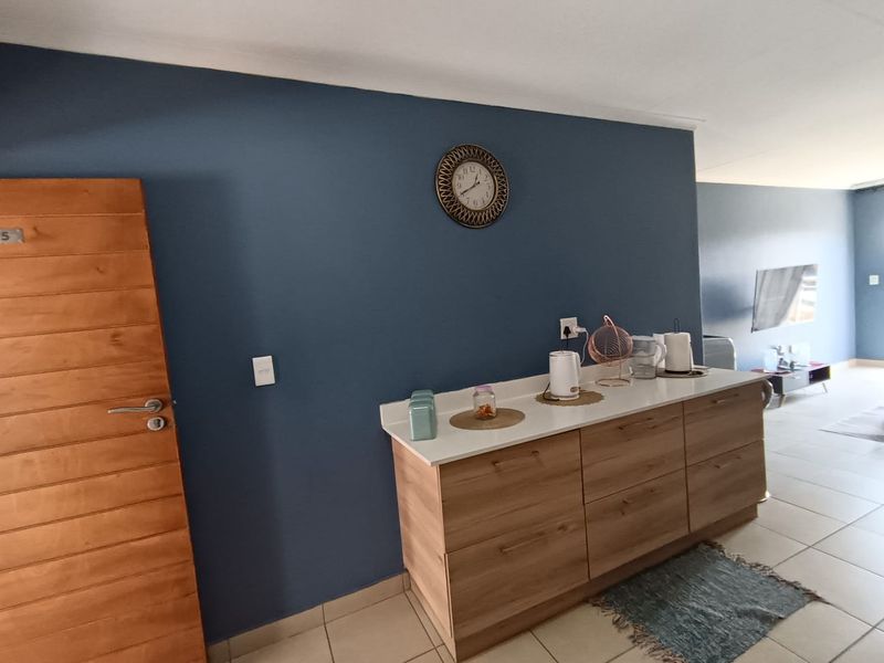 Open plan living area featuring a modern built-in sideboard with stone countertop, tiled flooring, and a feature blue wall.