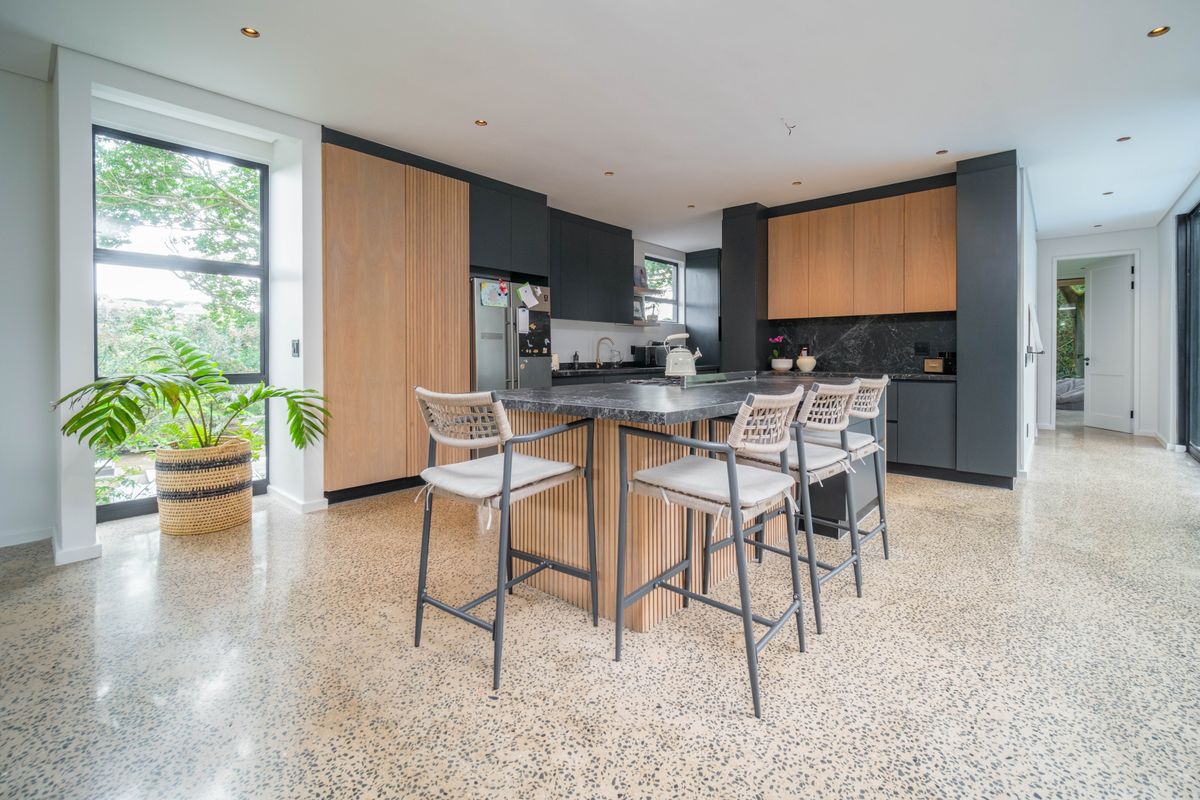 Modern kitchen featuring a large central island with stone countertop, custom cabinetry, and polished concrete flooring, offering a sleek and contemporary culinary space.