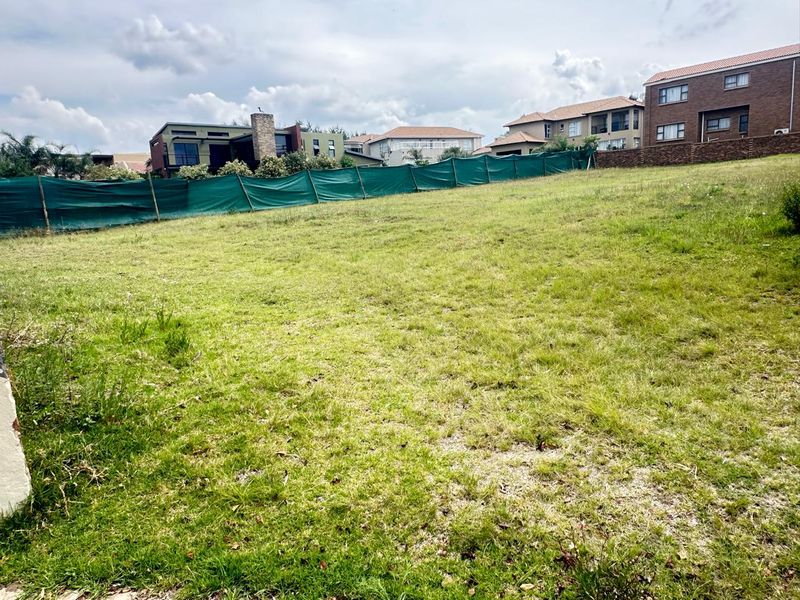 A vacant residential plot featuring a grass lawn and perimeter fencing, situated in a developed neighborhood.