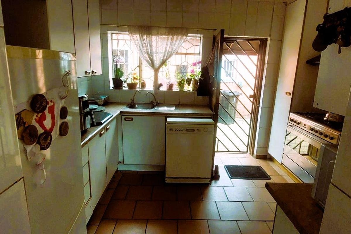 A functional kitchen featuring built-in cabinetry, a double sink, and a gas stove, with direct access to an exterior area.