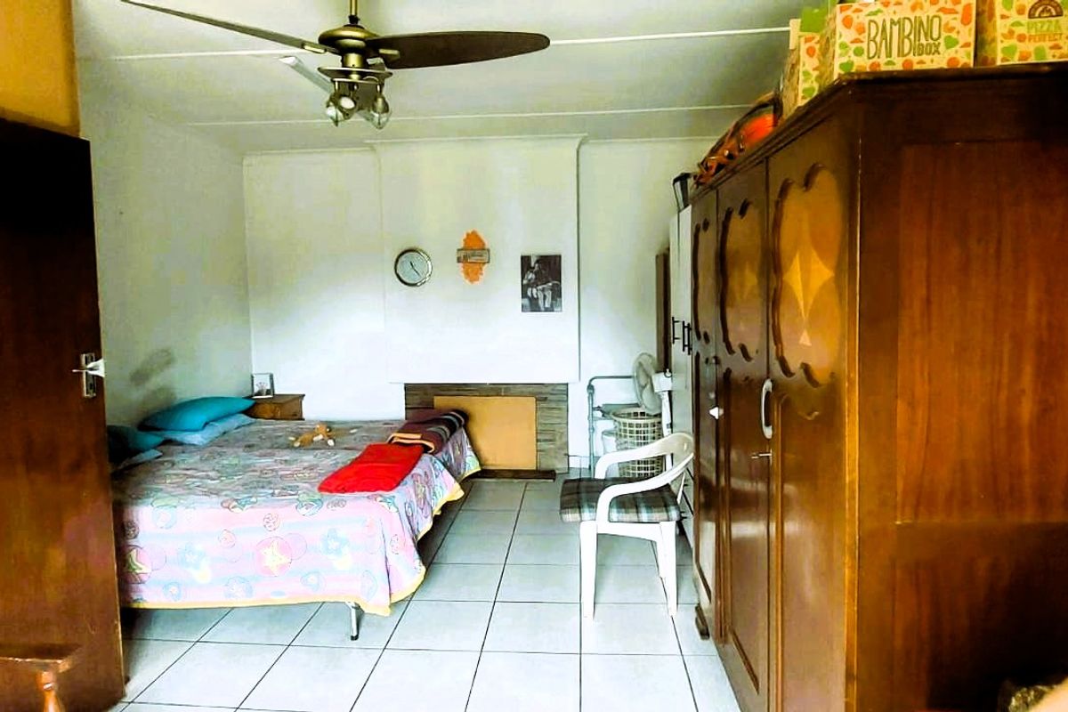 A bedroom featuring tiled flooring, a ceiling fan, and a built-in fireplace feature.