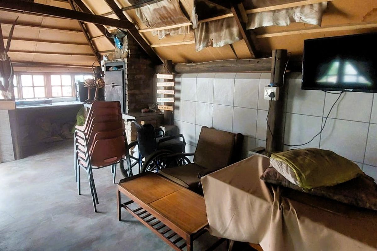 Rustic living area featuring exposed timber roof structure, tiled walls, and a built-in fireplace, offering a unique, character-filled space.