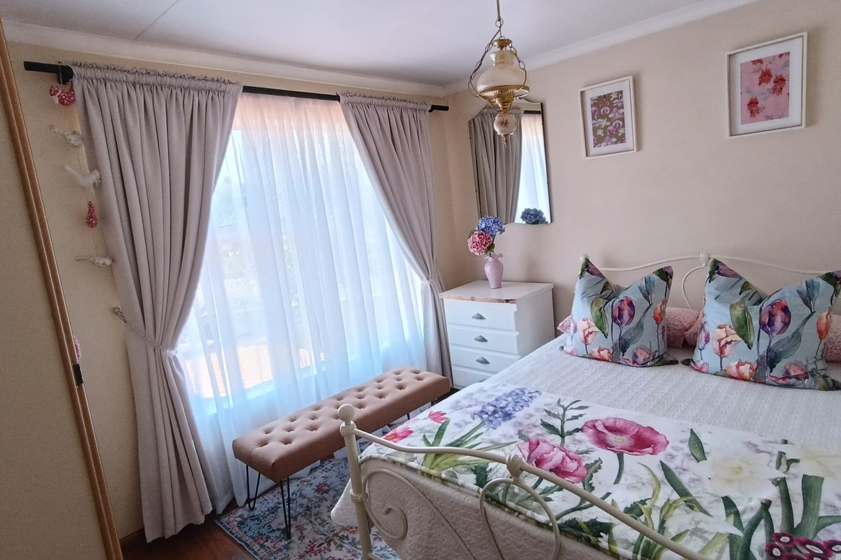 A cozy bedroom featuring a large window with floor-to-ceiling curtains, providing ample natural light and a comfortable atmosphere.