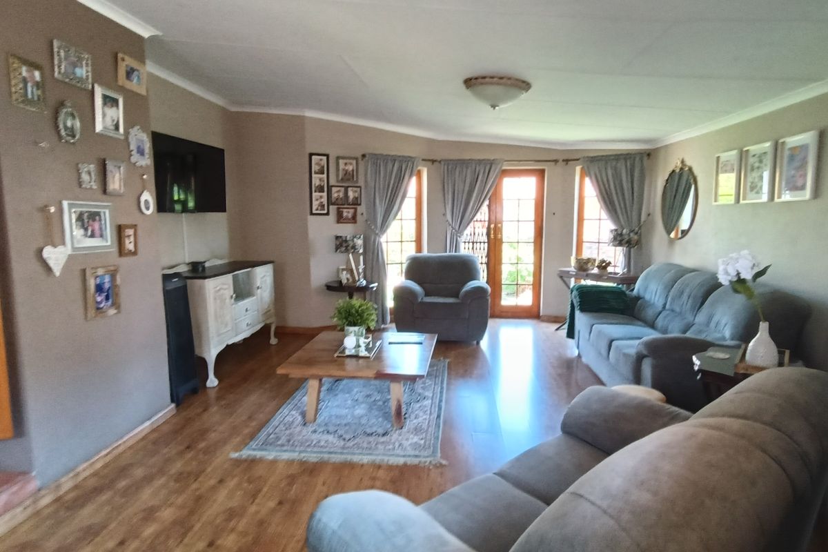 A comfortable living room featuring laminate wood flooring, neutral wall tones, and double glass doors providing natural light and access to the exterior.