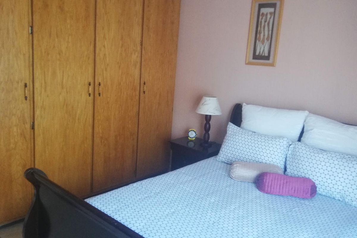 A bedroom featuring built-in wooden cupboards and tiled flooring.