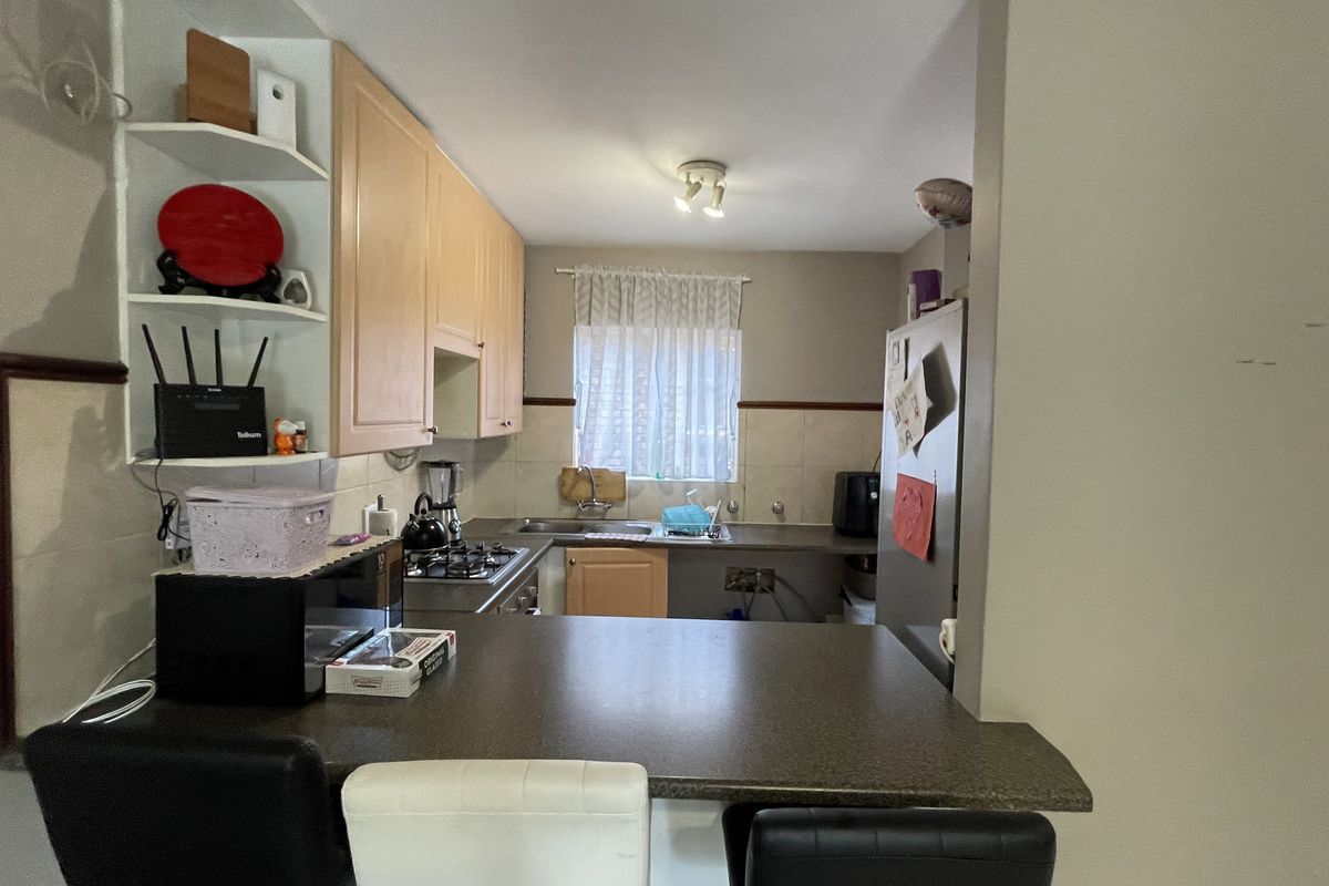 A functional kitchen featuring light wood cabinetry, a breakfast bar counter, gas hob, and tiled splashback, offering a practical layout for daily meal preparation.