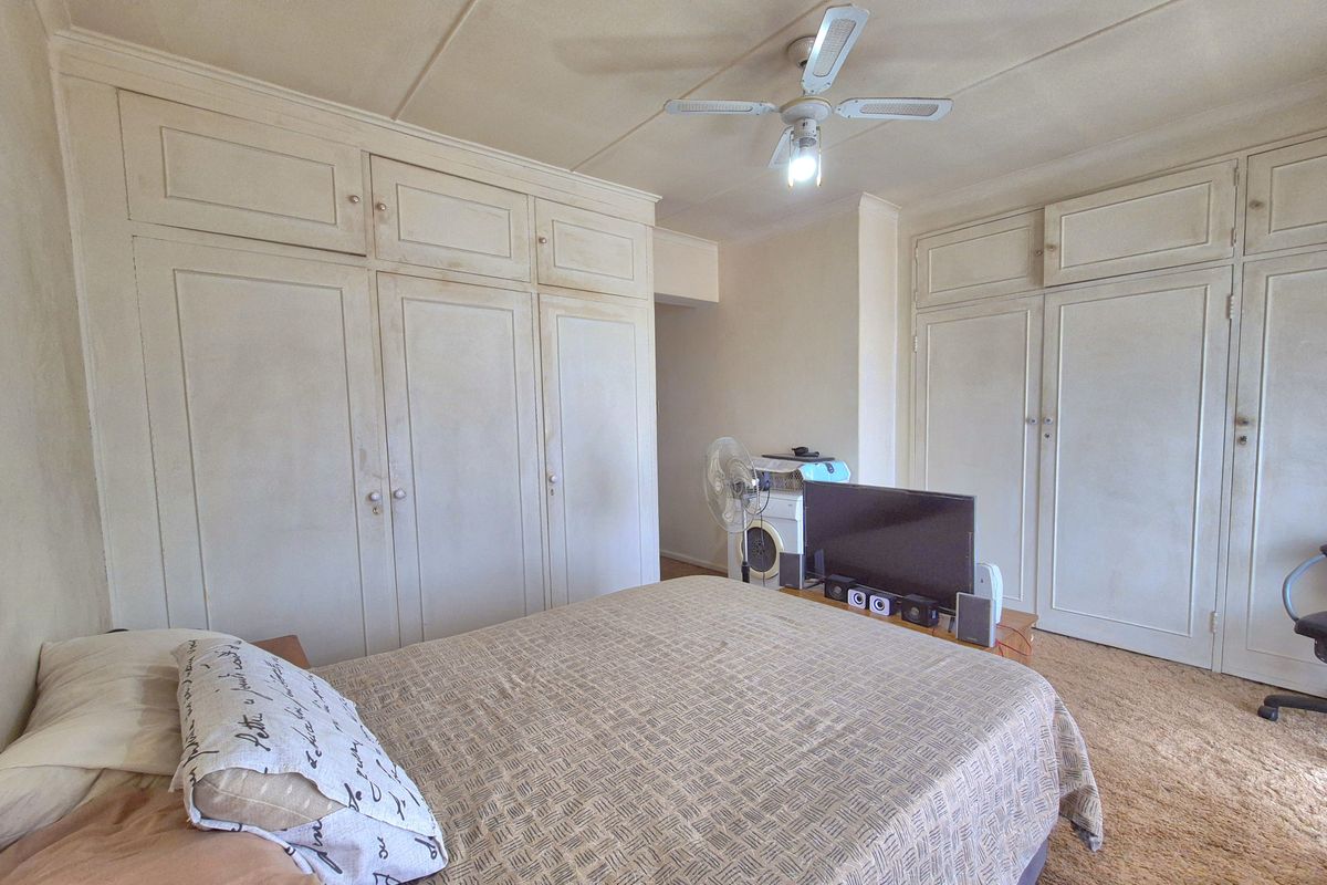 A bedroom featuring extensive built-in floor-to-ceiling cabinetry, carpeted flooring, and a ceiling fan.