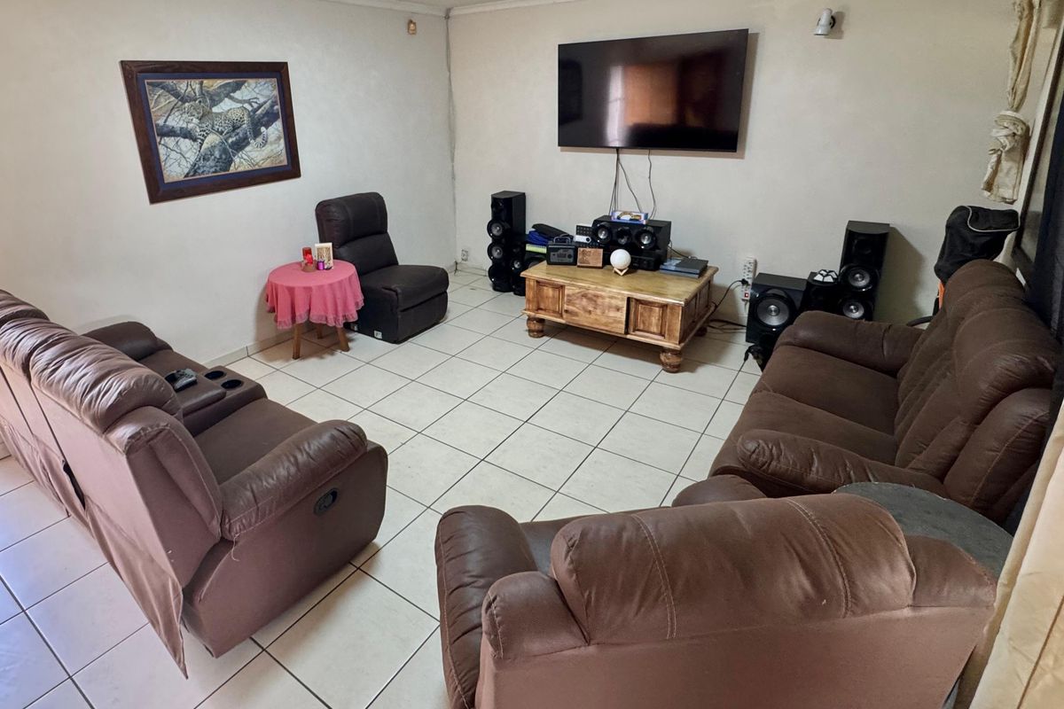 A living room featuring tiled flooring and wall-mounted television setup, providing a functional space for relaxation and entertainment.