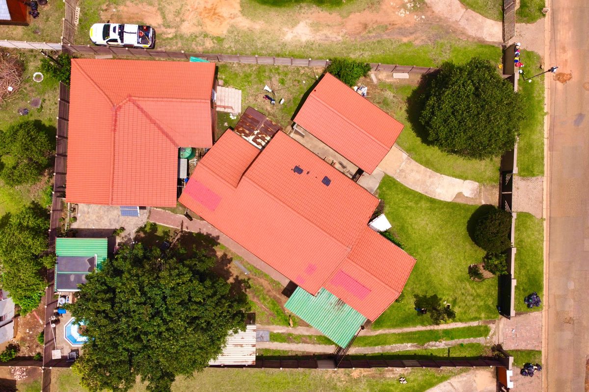 Aerial view of the property showing the main house, detached garage, swimming pool, and surrounding garden area on a spacious residential plot.