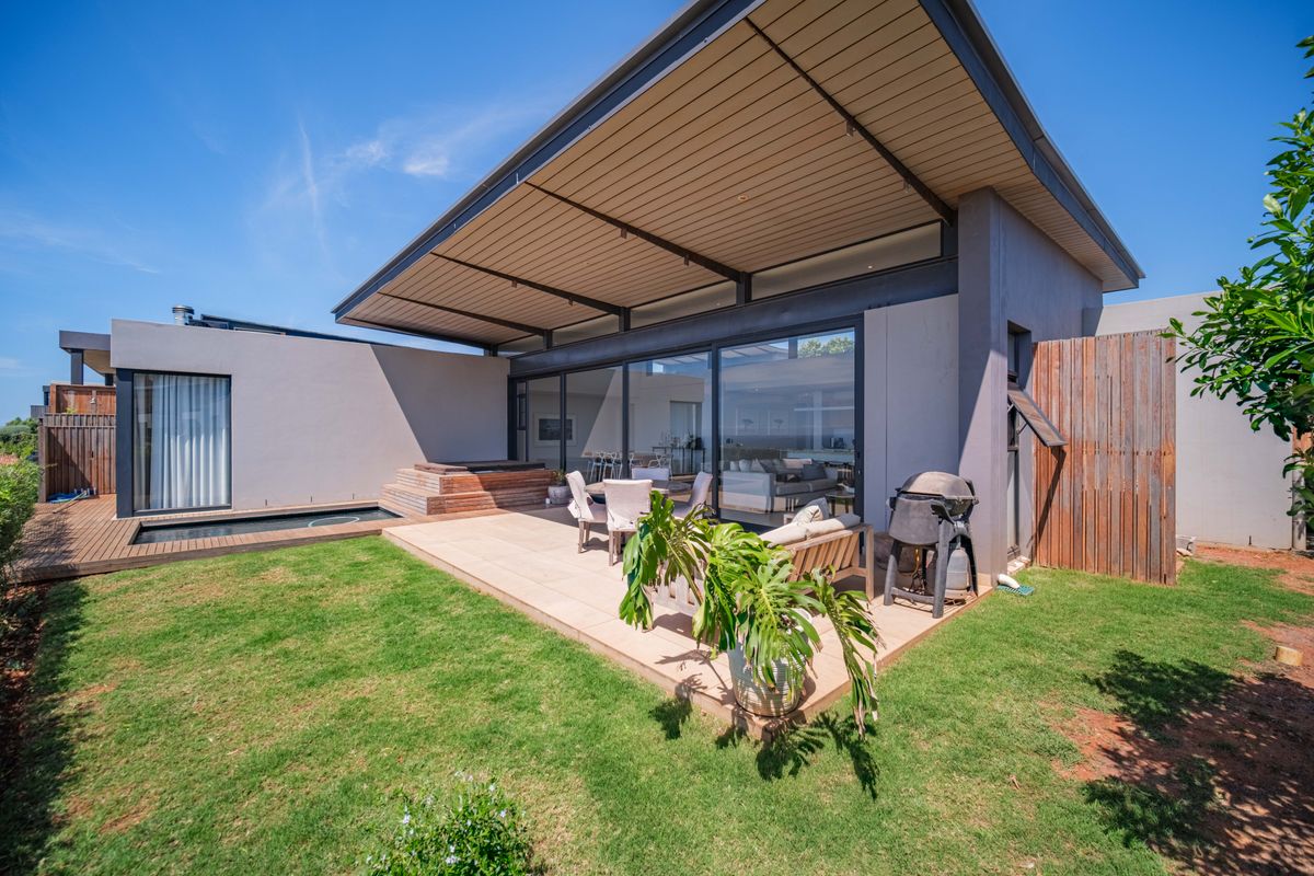 Modern rear exterior featuring a spacious covered patio, timber decking, integrated plunge pool, and large sliding glass doors connecting to the interior living space.