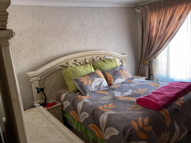 A bedroom featuring textured wallpaper and window treatments, offering a functional space ready for modern updates.