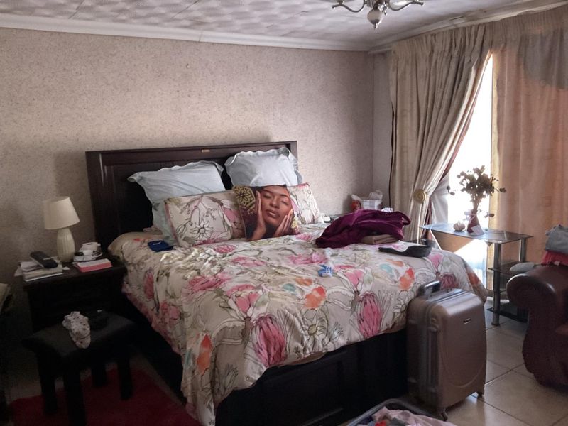 A bedroom featuring tiled flooring and a sliding door leading to an outdoor area, with potential for cosmetic updates to modernize the space.