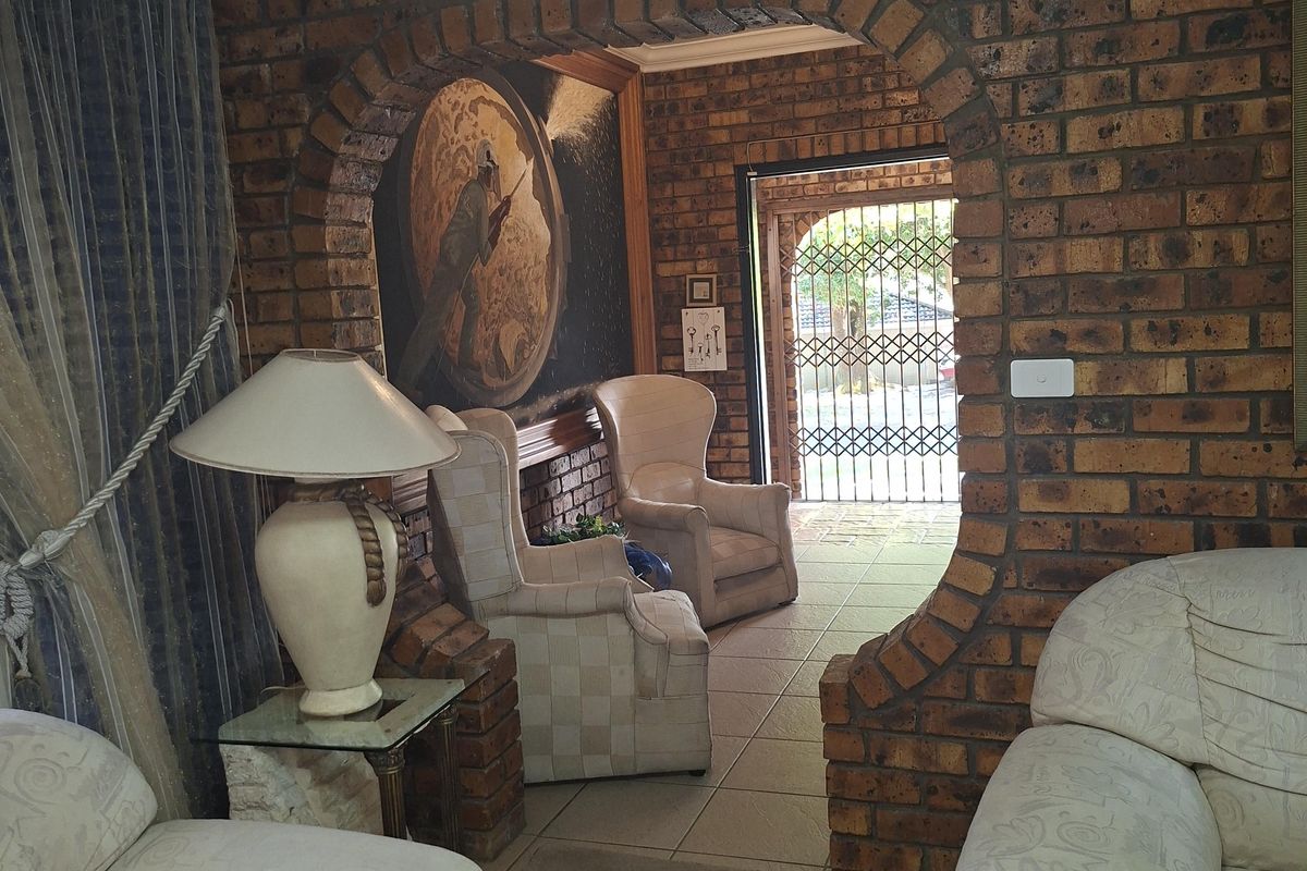 A living area featuring a distinctive arched brick entryway leading to an exterior door with security gate.