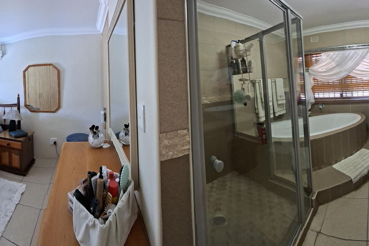 Spacious bedroom featuring an en-suite bathroom with a corner soaking tub, glass-enclosed shower, and dual vessel sinks on a vanity.