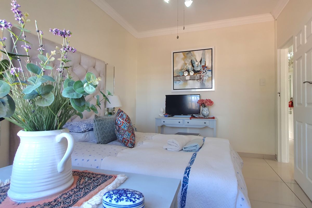 A well-lit bedroom featuring tiled flooring, crown molding, and a neutral color palette, providing a comfortable and functional living space.