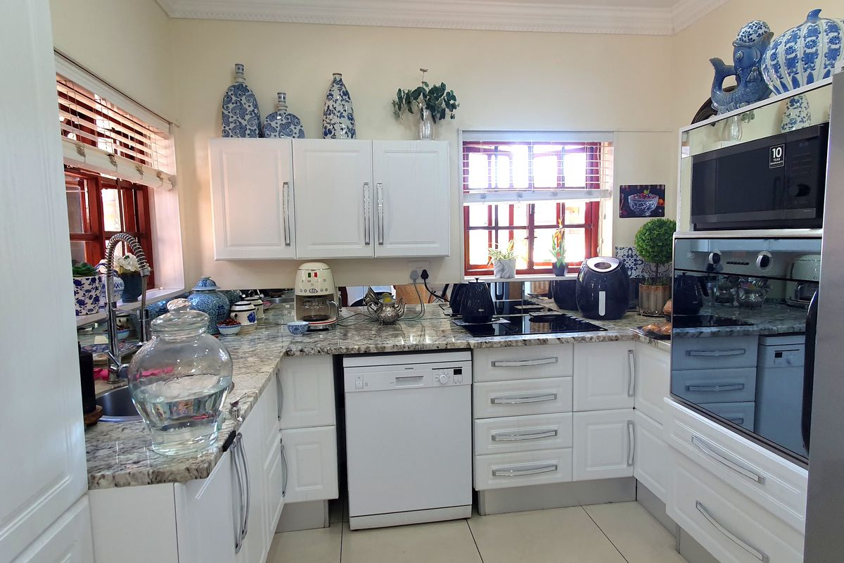 A well-maintained kitchen featuring white cabinetry, granite countertops, a built-in oven, microwave, and integrated dishwasher, offering a functional and bright cooking space.