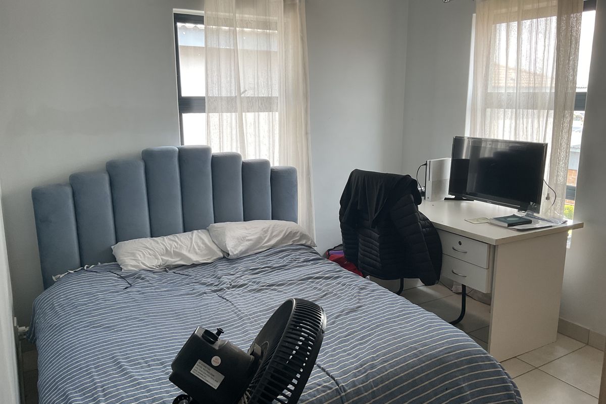 A bedroom featuring tiled flooring and two windows with curtain rods.
