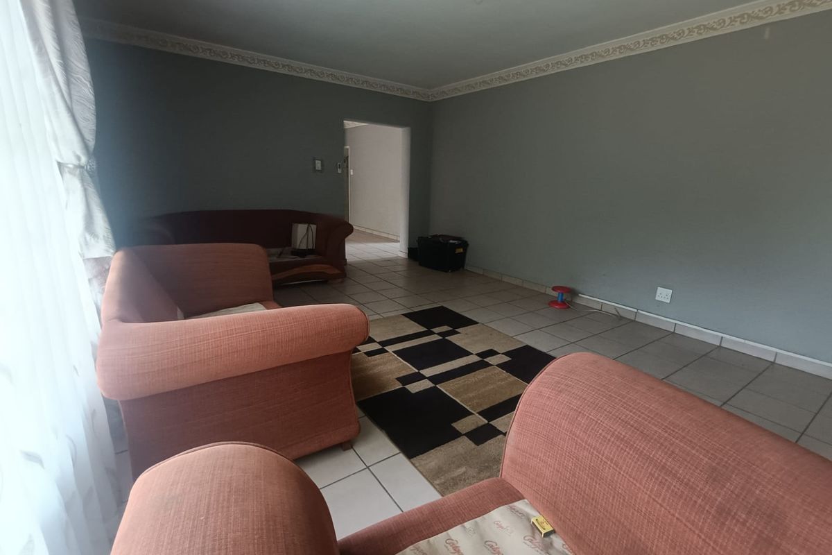 A living room featuring tiled flooring, decorative ceiling rose, and crown molding, providing a neutral base for interior design.