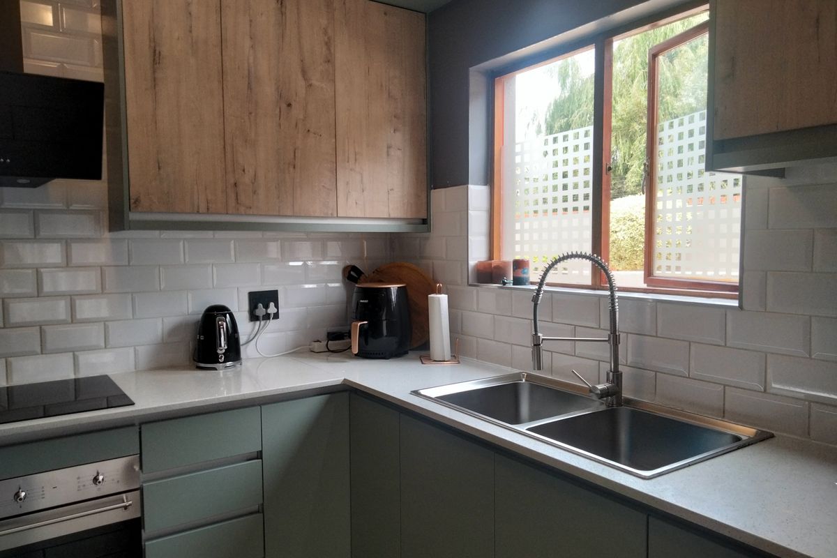 Modern kitchen featuring two-tone cabinetry, stone countertops, subway tile backsplash, integrated oven, and a double sink with a gooseneck faucet.