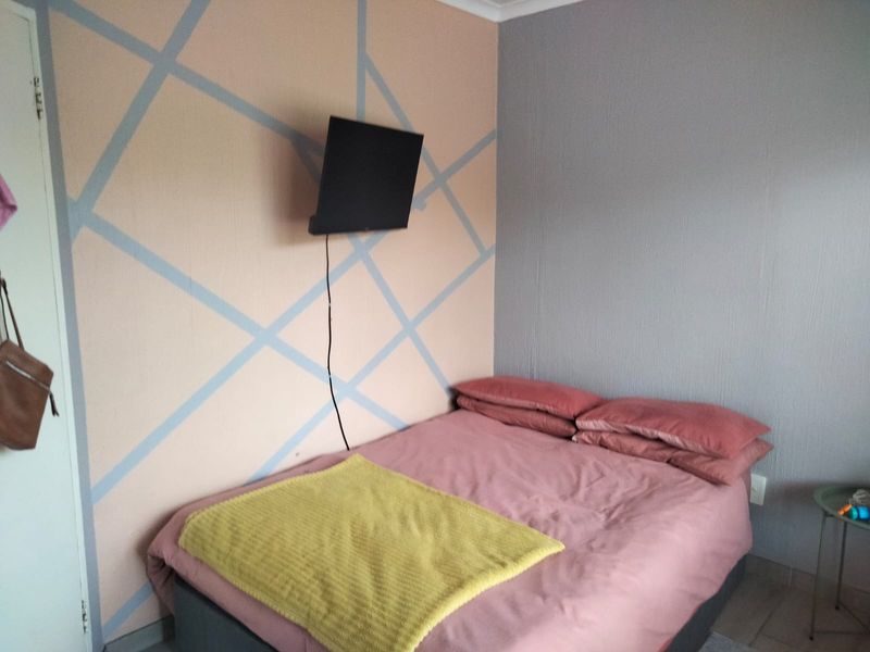 A bedroom featuring a wall-mounted television and decorative painted wall accents.