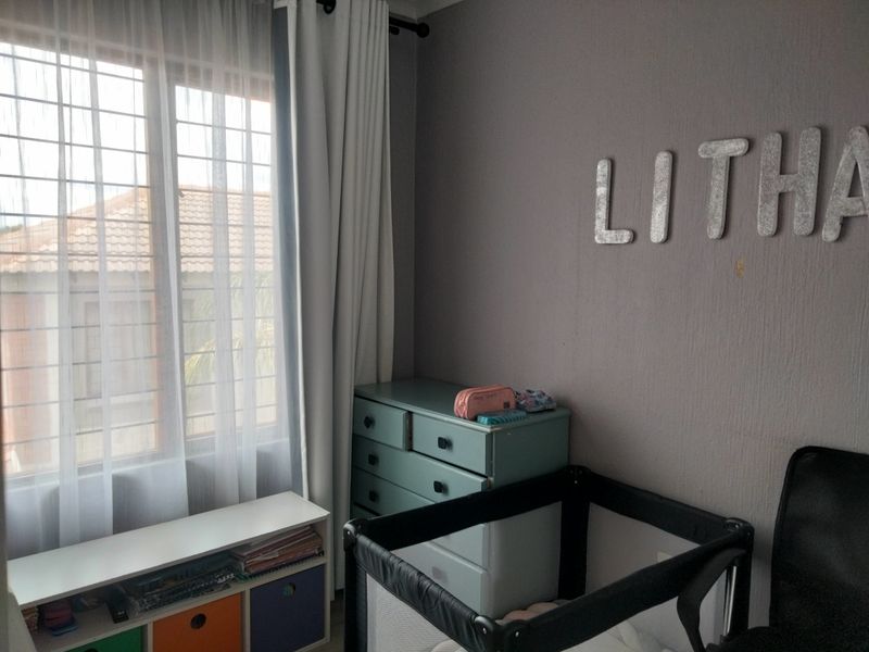 A bedroom featuring a window with security bars and neutral wall finishes, providing a functional space for a child's room.