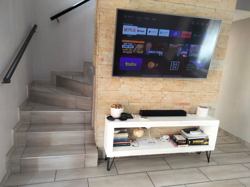 Living area featuring a stone veneer feature wall, tiled flooring, and a staircase with a modern handrail.