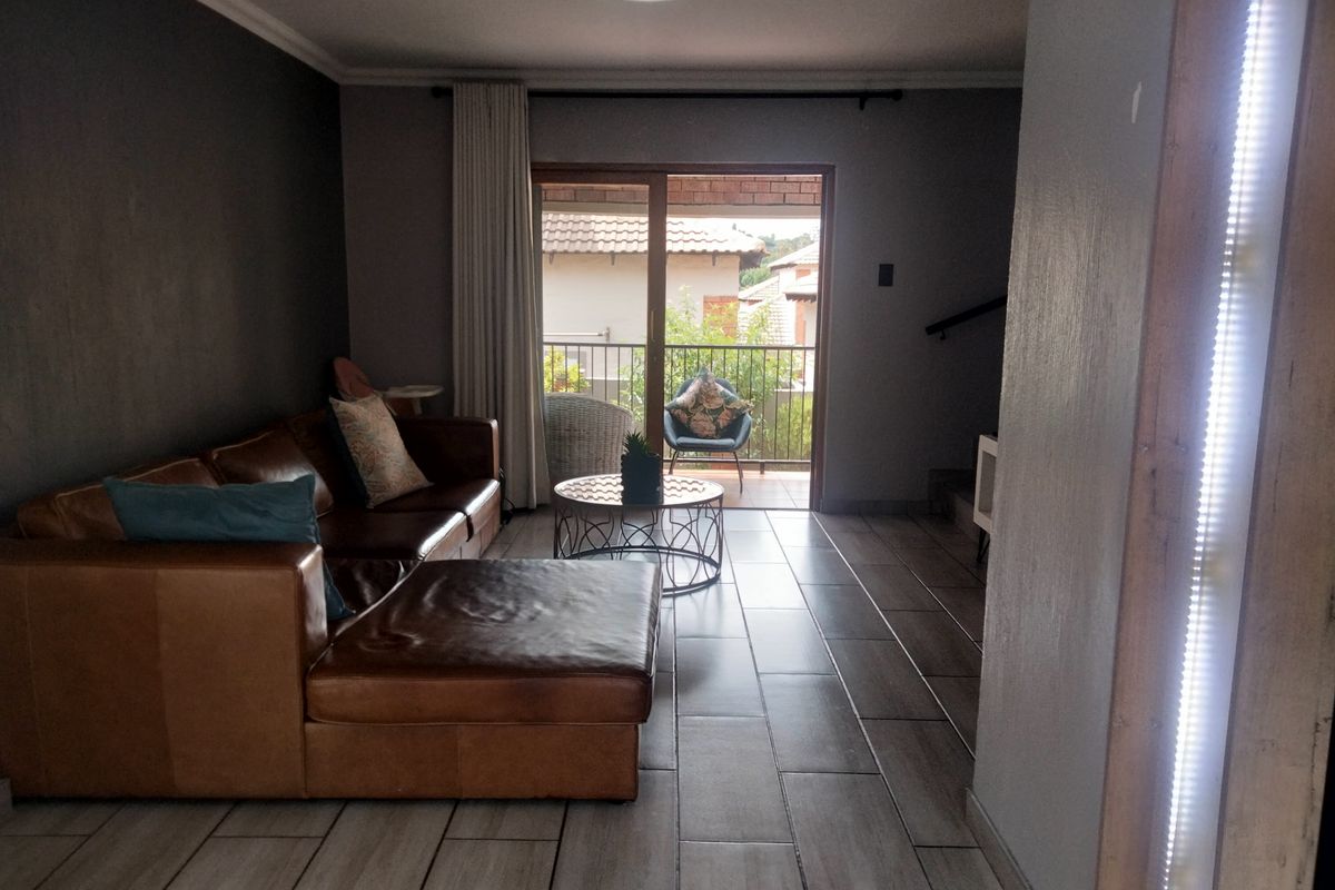 A living room featuring tiled flooring and a sliding glass door that provides direct access to an outdoor balcony area.