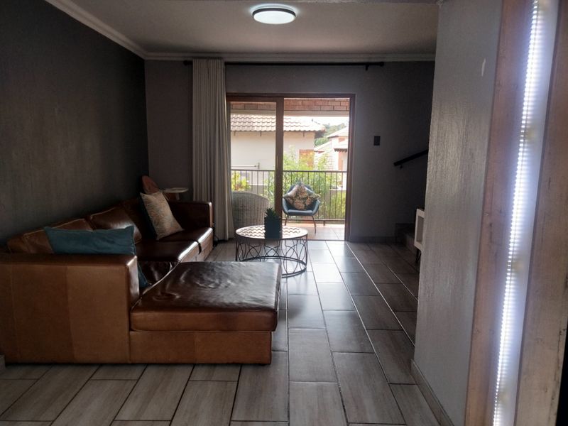 A living room featuring tiled flooring and a sliding glass door that provides direct access to an outdoor balcony area.