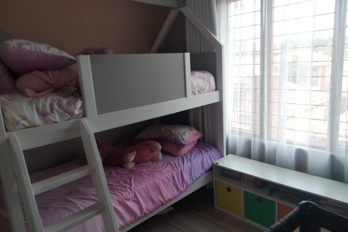 A bedroom featuring tiled flooring and a large window with security bars, providing natural light to the space.