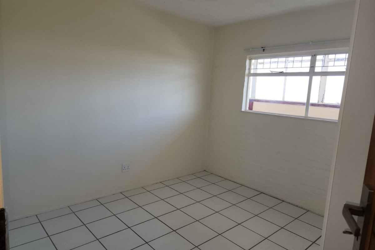 A simple, empty bedroom featuring tiled flooring and a single window, providing a blank canvas for potential interior design updates.